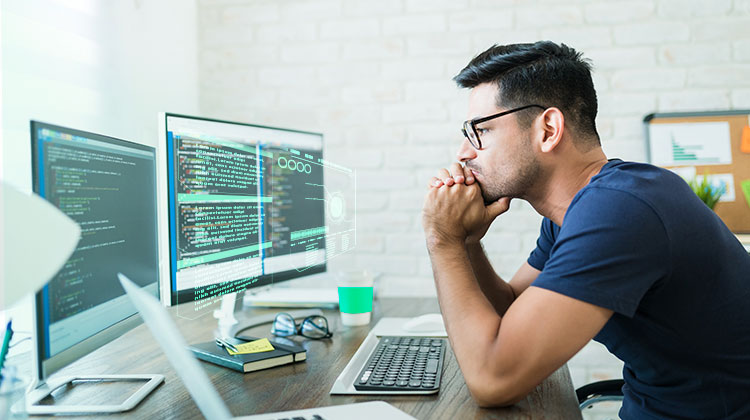 Male mobile app developer working on a desktop computer.