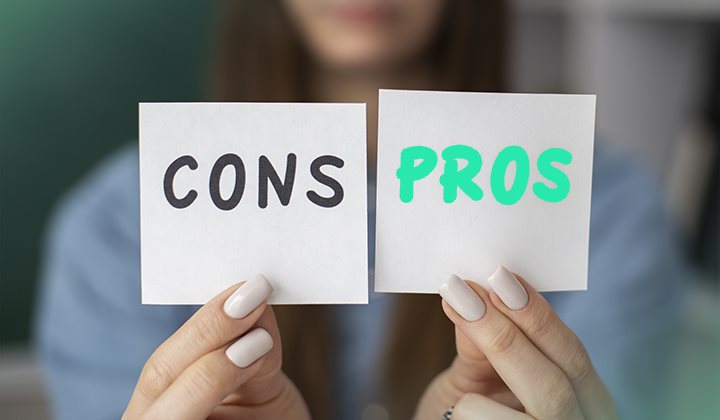 Woman's hands holding two notes that say "CONS" and "PROS"